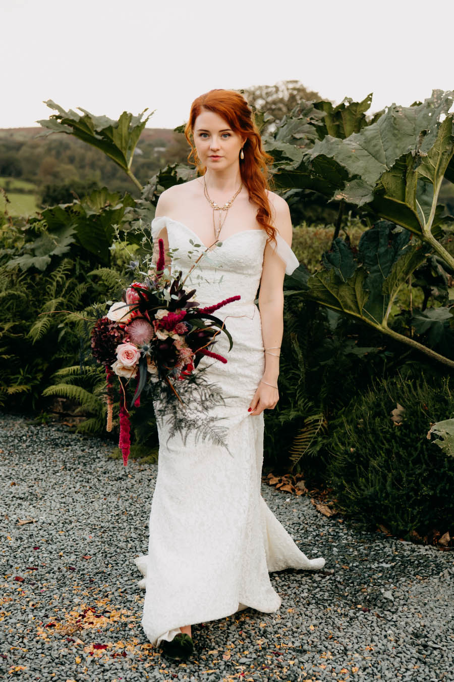 A bridal bouquet of luxurious blooms, textured foliage, and feathers intricately woven together prove the highlight of a Gothic-inspired wedding at Trevenna Barns Cornwall. The bouquet and wedding floristry by Artem Florum.