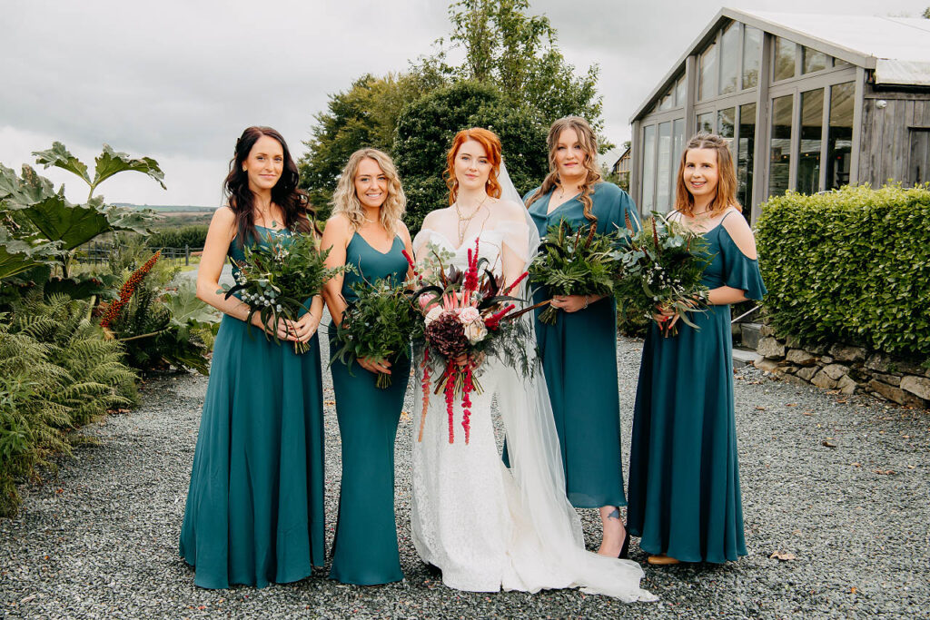 The bridesmaids' bouquets exuded elegance, bursting with textured foliage, feathers, and delicate hints of white limonium. Wedding floristry by Artem Florum.